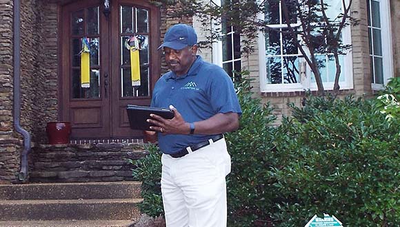 Clarence Williams, home inspector in Mississippi, in front of a house going over a home inspection report.